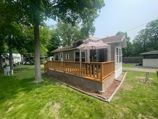 Home with a raised wooden deck and patio umbrella in a leafy yard.