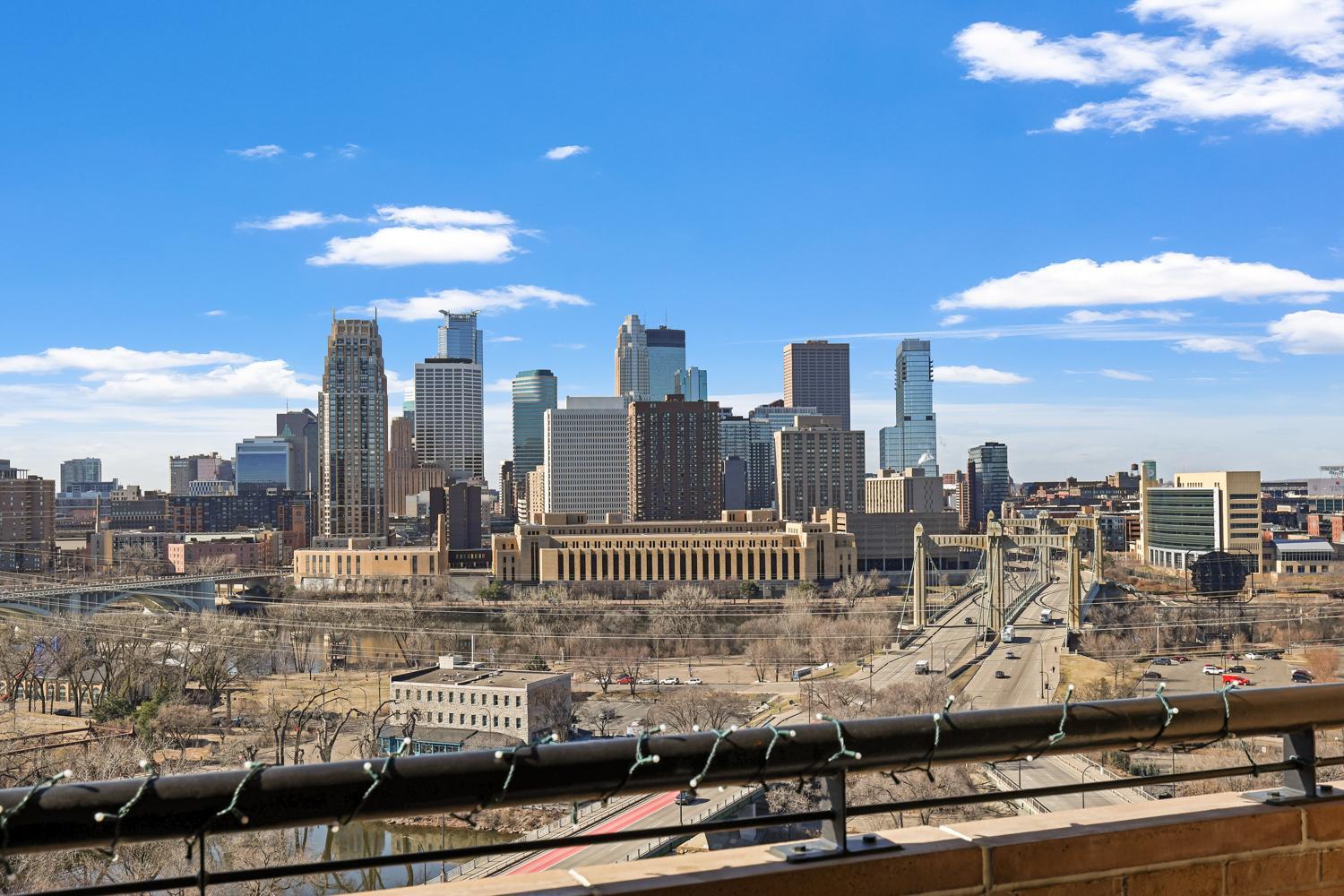 Downtown Minneapolis skyline and Mississippi River bridges viewed from a balcony.
