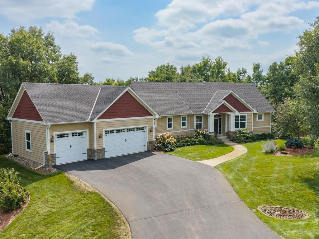 Single-story beige home with red gables, two garage doors, and a curved walkway across the front lawn.