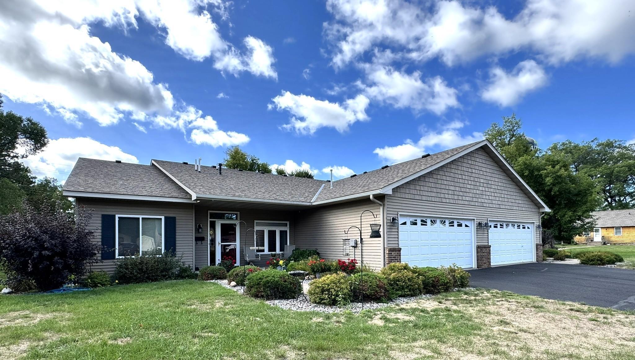 Gray single-story home with a two-car garage and landscaped flower beds.