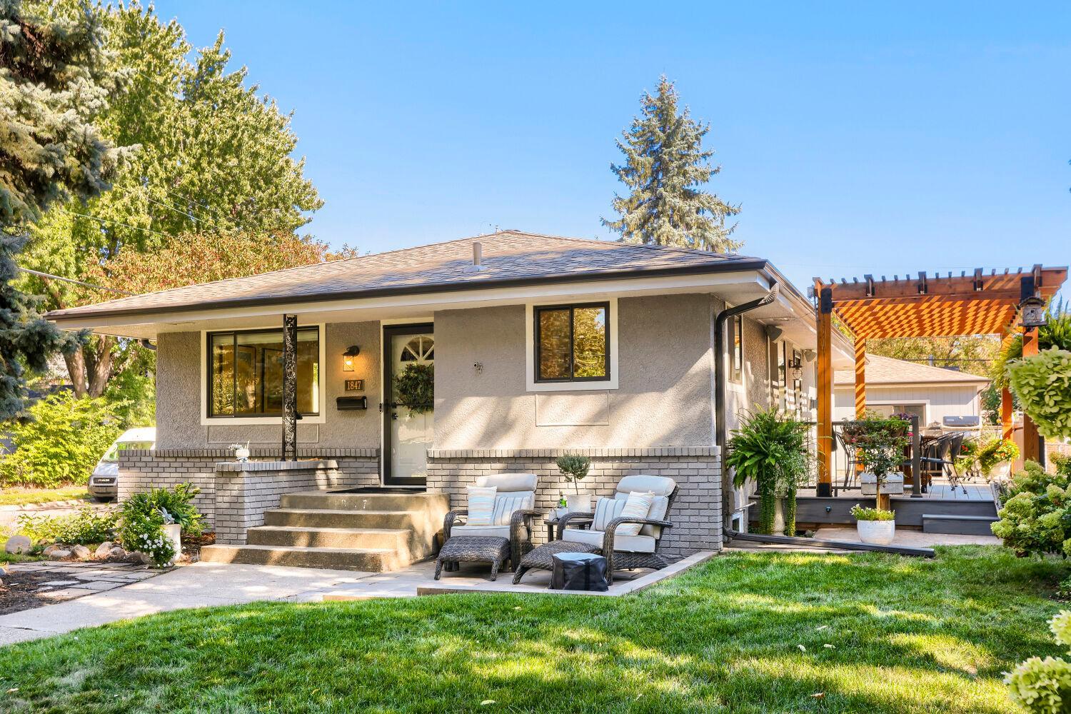 Single-story home with brick accents, a furnished front patio, and a wooden pergola beside the deck.
