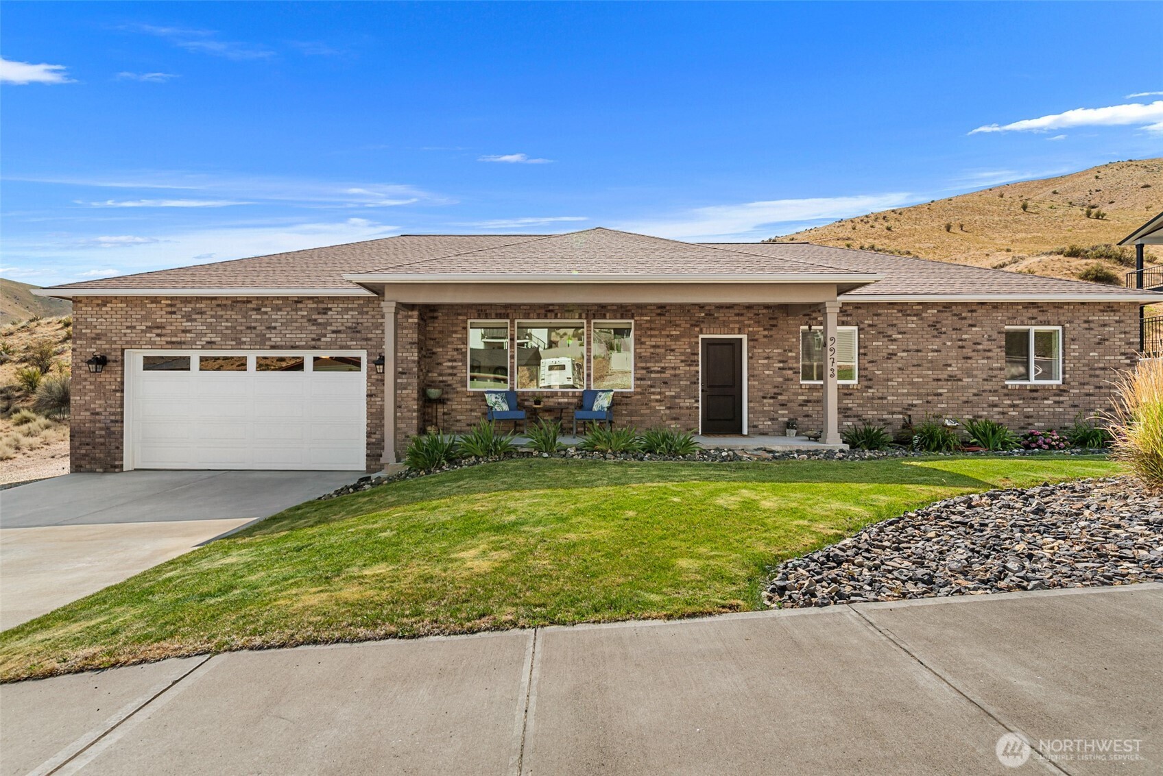 Single-story brick home with an attached garage, covered porch, and landscaped lawn.