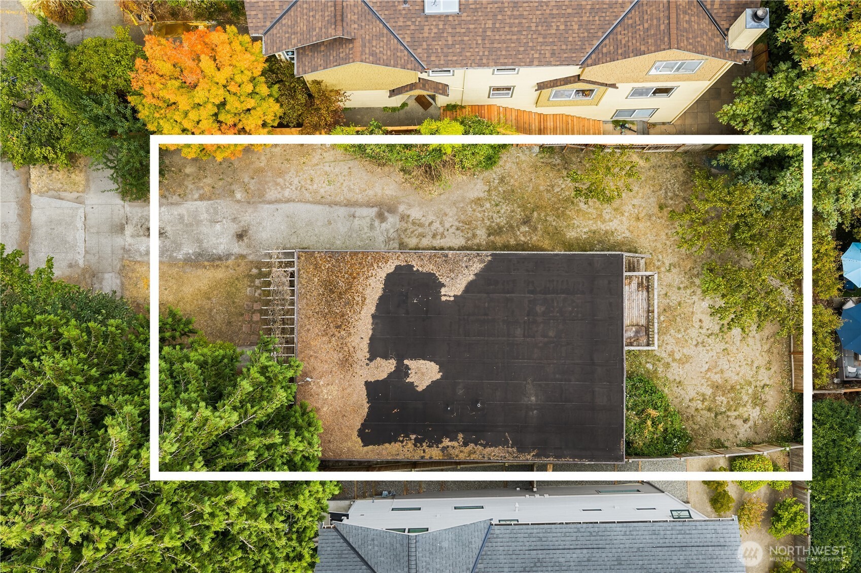 Aerial view of a residential lot outlined in white, surrounded by trees and neighboring homes.