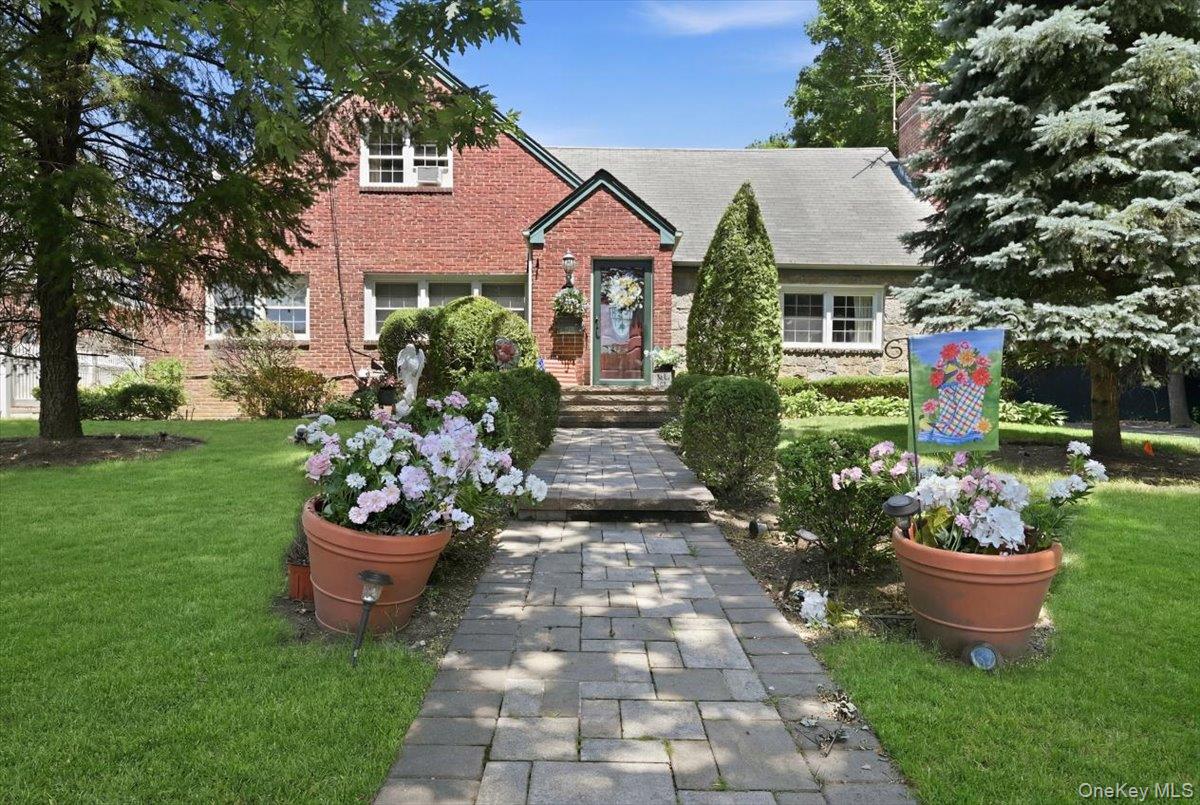 Brick house with a stone walkway leading through flower beds to the front door.