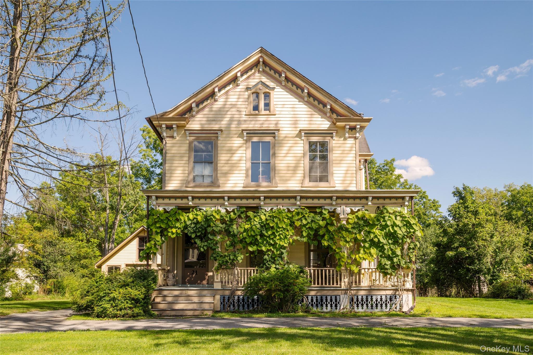 Cream clapboard house with ornate trim and a vine-covered front porch.