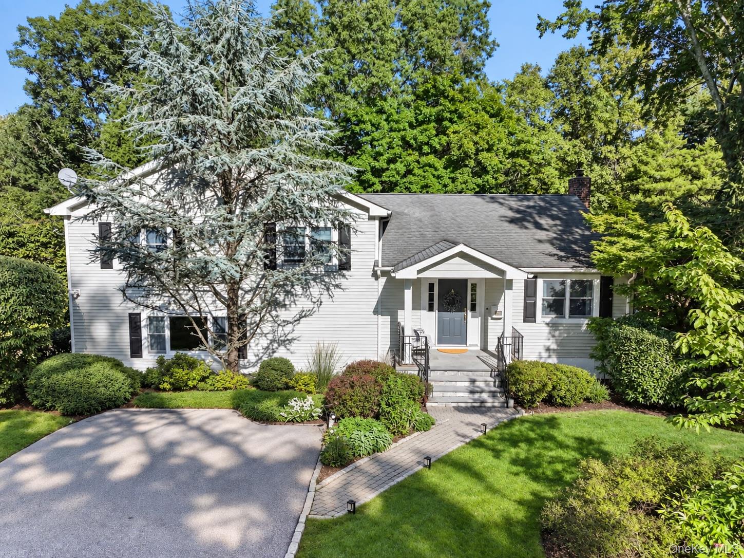 White-sided house with a covered front porch, landscaped gardens, and a curved driveway.
