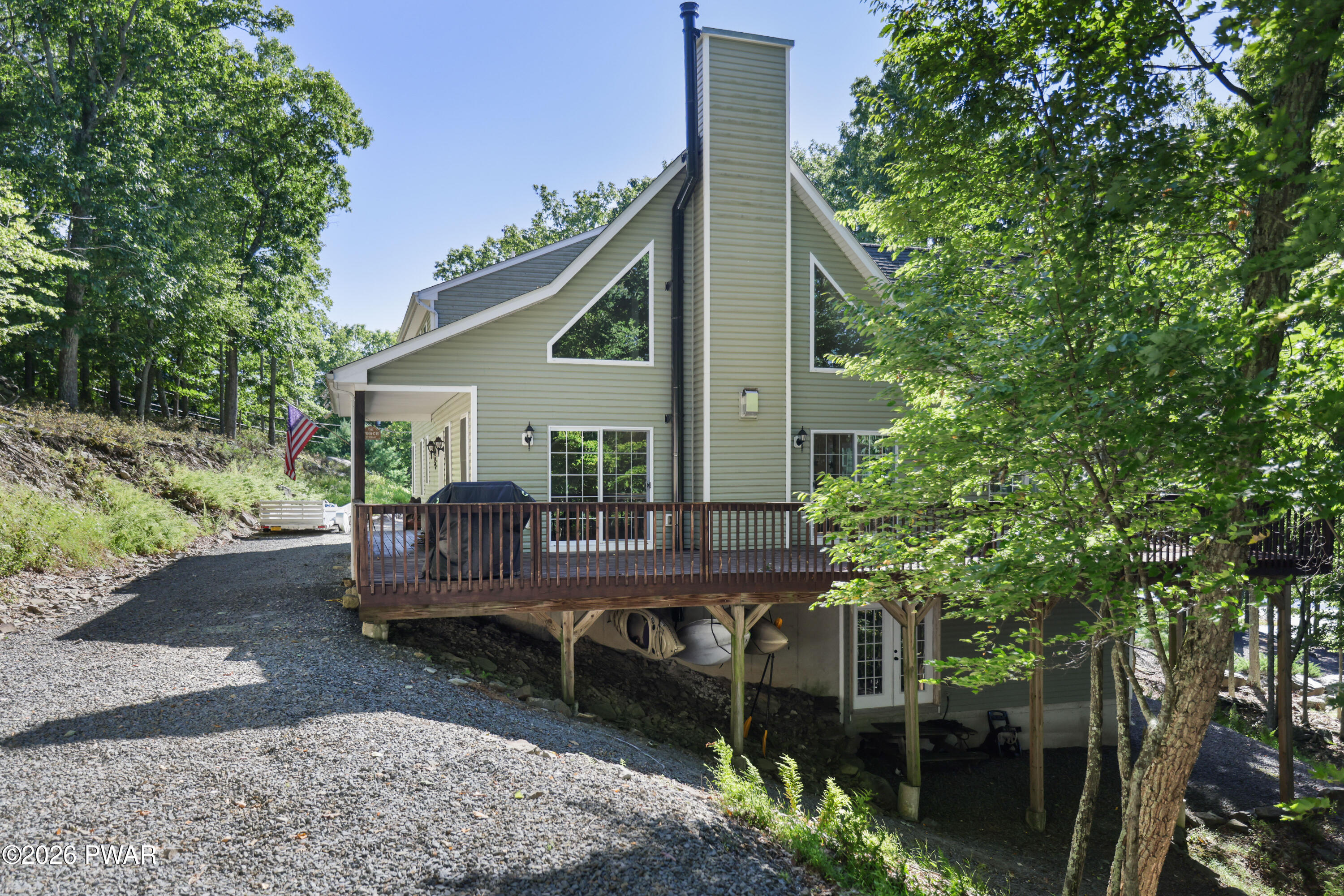 Wooded home with a raised deck and kayaks stored beneath it.