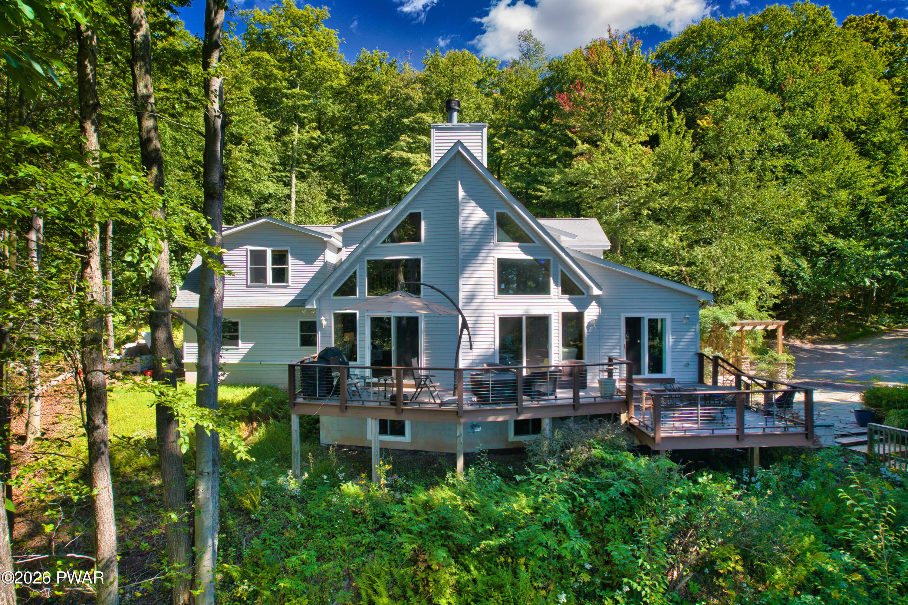A-frame house with a multi-level deck nestled among dense trees.