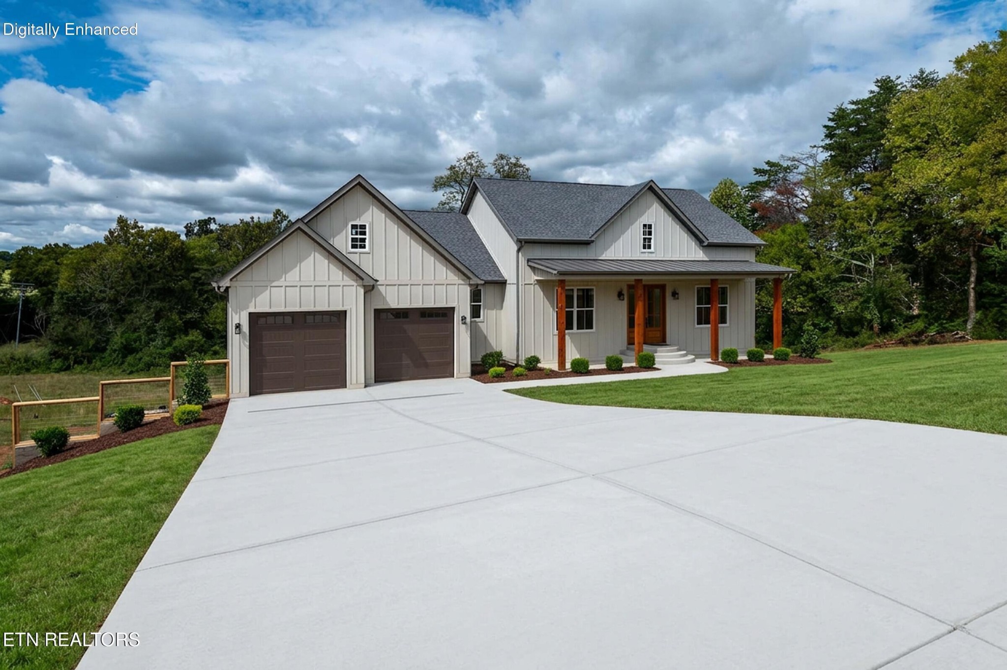 Two-story farmhouse with a covered porch, two garage doors, and a wide concrete driveway.