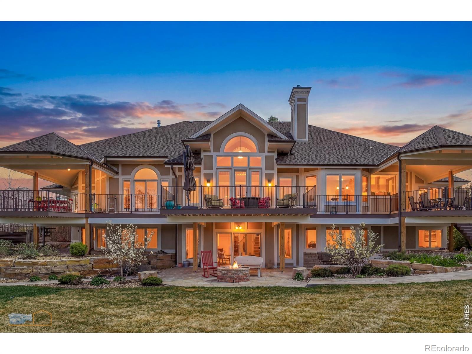 Large two-story home at dusk with an expansive deck and backyard fire pit.