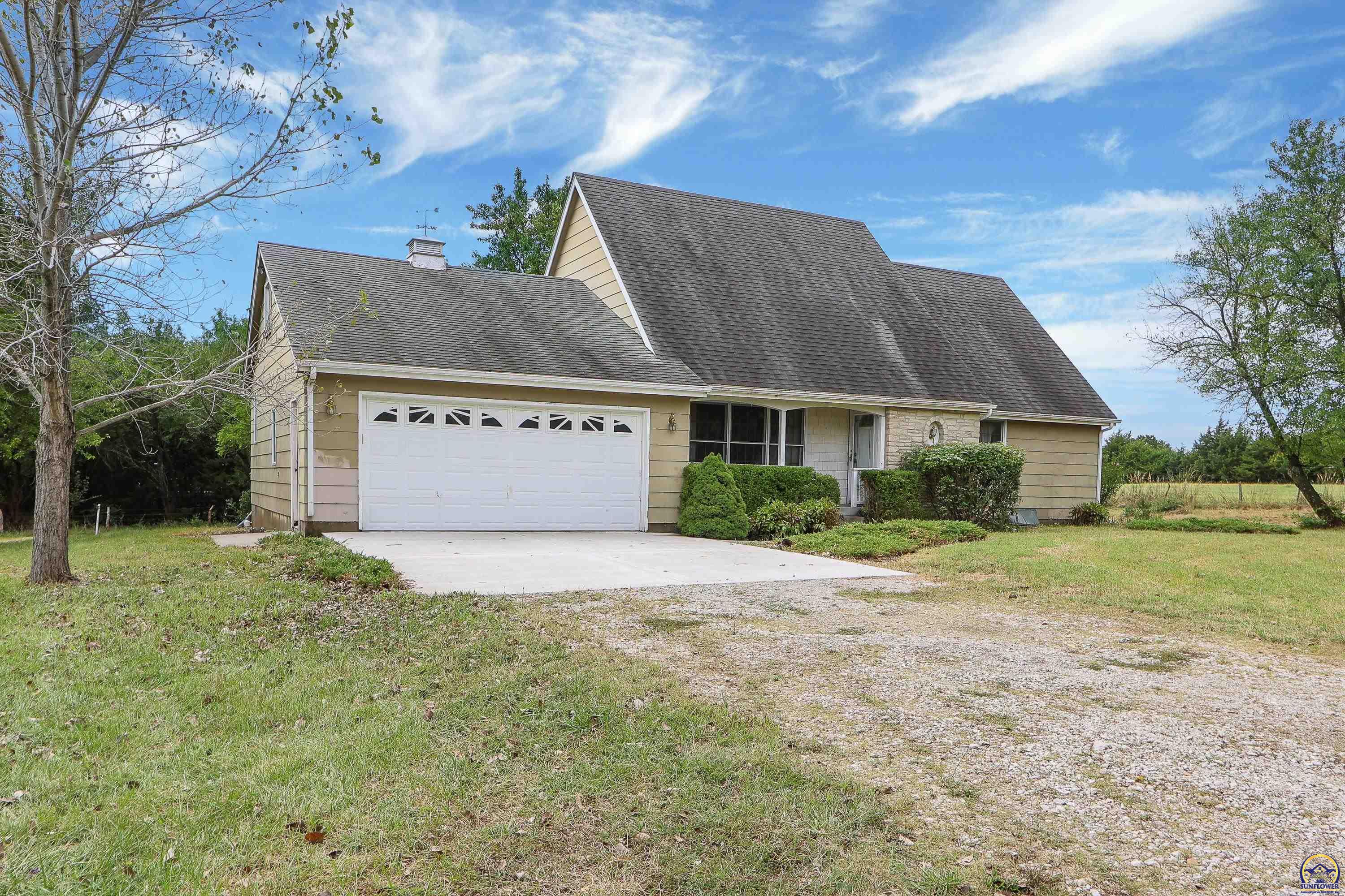 Beige gabled house with an attached double garage and broad gravel driveway.