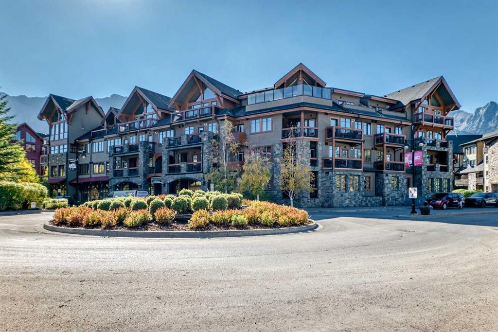 Spring Creek condominium building with stone façades, timber balconies, and mountain peaks behind it.