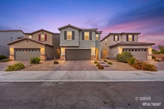 Three stucco homes with attached garages and desert landscaping at dusk.